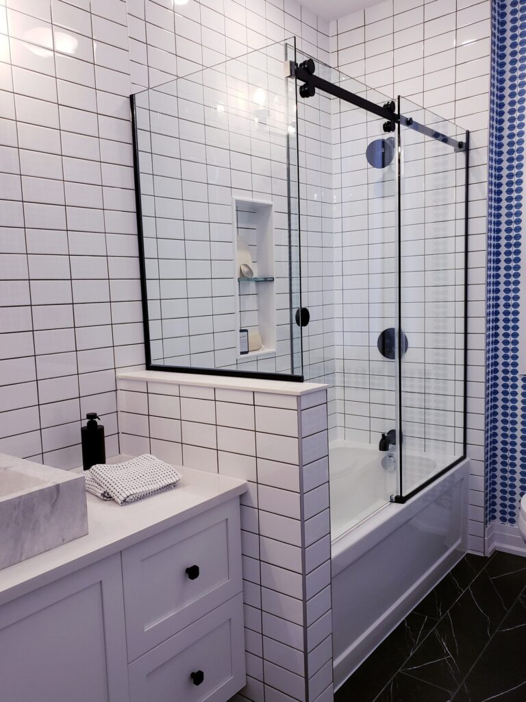 Glass shower with white tiled wall